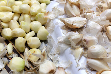 Peeled Garlic Cloves and Papery Husks Arranged on a White Background