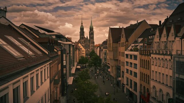 Scenic view of Nuremberg&rsquo;s old town with St. Lorenz Church framed by historic and modern buildings, bustling pedestrian street, and dramatic evening clouds.
