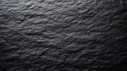 Dark textured surface with rough uneven features and a gradient from light to dark