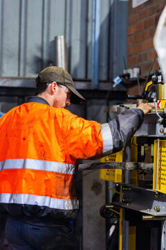 young mechanic tradie using workshop mate press tool workstation to repair car components