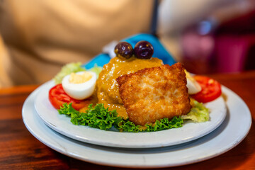 Nahaufnahme eines traditionellen peruanischen Gerichts mit gelber Soße, Fleisch und frischer...
