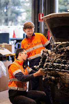 Two male mechanics inspecting vehicles engine in workshop