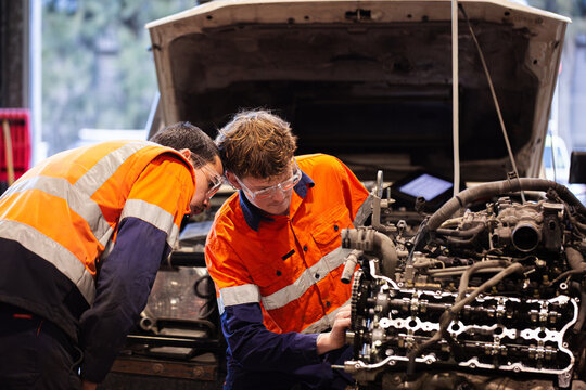 Two male mechanics inspecting vehicles engine in workshop