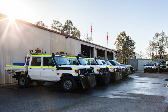 Fleet of white utility vehicles lined up outside mechanics repair shed