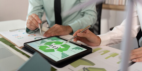 ESG Strategy Discussion. Professionals analyzing sustainability metrics on tablet.