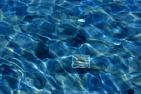 Rippled Blue Water Surface with Sunlight Reflections and Floating Objects