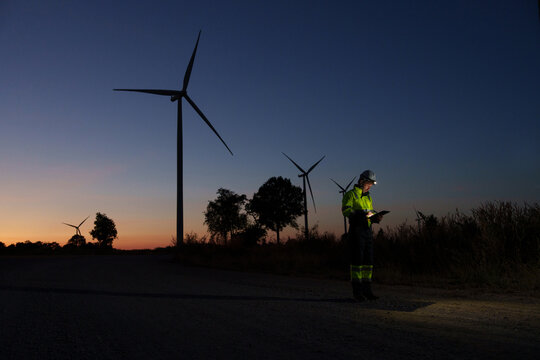 Engineer technician working at wind turbine power plant during sunset Renewable energy solutions for climate change Clean energy