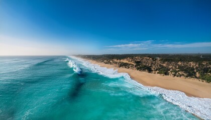 Obraz premium aerial view of a turquoise ocean washing onto a sandy beach creating beautiful foamy white waves and a calming natural landscape