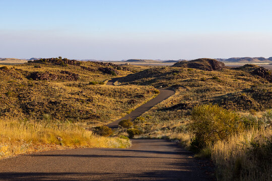 pilbara landscape with winding sealed road leading through dry vegetation