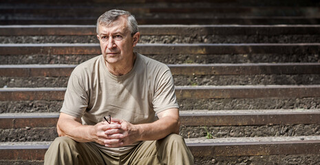 Pensive European senior man, emotional portrait of reflection and life challenges. Emotive portrait of a 55–65 year old man outdoors