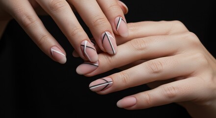 Fototapeta premium Beautifully manicured woman's hands displaying a stylish geometric design of black and white lines on nude polish