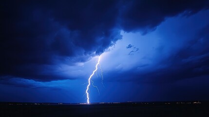 Dramatic lightning striking ground under dark blue stormy night sky