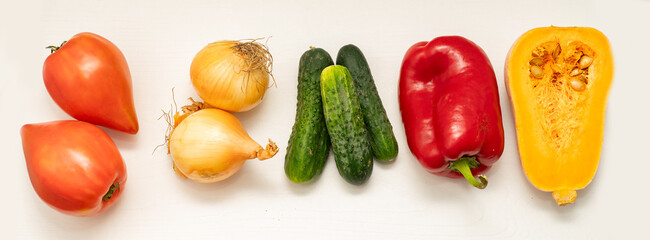 Assortment of freshly harvested farm vegetables including tomatoes, onions, cucumbers, red bell pepper, and butternut squash on a white background