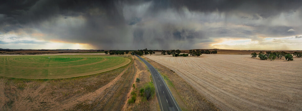 Aerial view of a dramatic stormfront approaching over farmland beside a country road