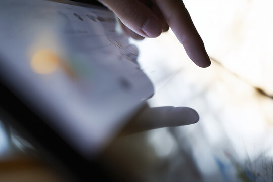 Close up view of hand interacting with touchscreen device, showcasing finger gently tapping screen. background is softly blurred, creating modern and tech savvy atmosphere