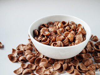 Chocolate corn flakes with milk in a bowl on white background