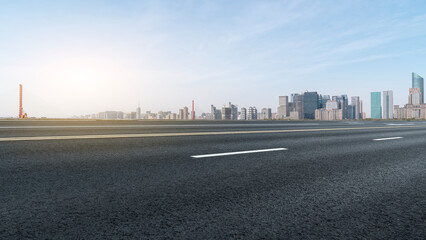 Empty Road Leading to Modern Cityscape Under Blue Sky