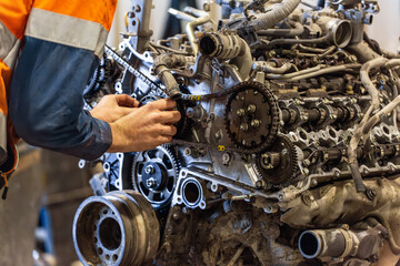 Male mechanic working on a complex engine inside industrial workshop