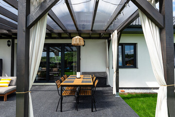The terrace behind the house is made of beams, the roof is covered with polycarbonate.