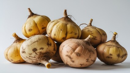 A group of onions with papery skin and roots, isolated on a light background.
