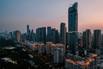 Modern skyline at dusk with illuminated skyscrapers.