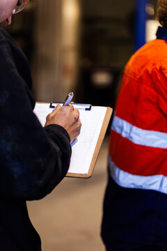Male mechanic writing on clipboard in workshop