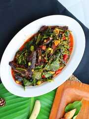 Stir-fried kale with canned fish in tomato sauce, combining fresh crunch from greens with the savory-sweet flavor of the fish, creating a simple yet delicious Thai comfort dish.