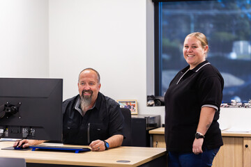 Business owner seated at desk in office indoors chatting with receptionist office lady