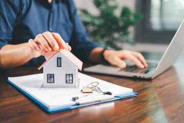Female hand holds small miniature toy house, symbolizing woman dream of moving into her own home-real estate concept represents property investment, mortgage planning, insurance for secure future.