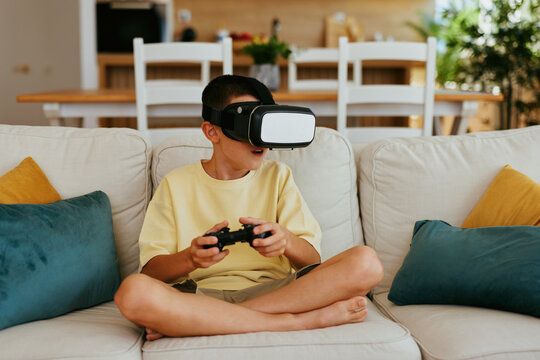 Child having fun playing with vr glasses and a controller in the living room