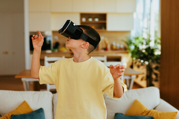 Young boy wearing vr headset exploring virtual world, gesturing with hands in modern living room
