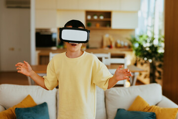Young boy experiencing virtual reality using vr headset, interacting with metaverse in living room