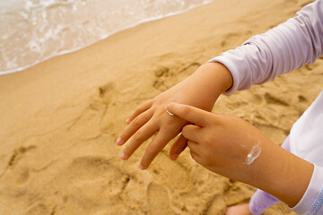 Child smears sunscreen on his hands