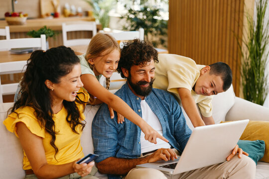 Happy family doing online shopping using laptop and credit card at home