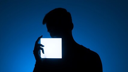 A minimalist silhouette of a person holding a glowing rectangular object in cool blue tones.