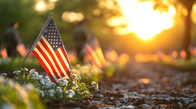Flags honor veterans during sunset at a memorial site with flowers and trees