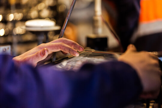 Aussie workman mechanic working on vehicle diagnostic device inside industrial workshop