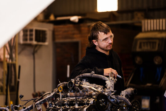 Aussie workman mechanic standing beside vehicle internal engine inside industrial workshop