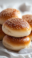 Freshly baked sesame buns stacked together, showcasing their golden brown surface and soft texture.