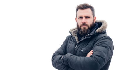 A bearded man in a winter coat with fur trim standing with his arms crossed looking at the camera
