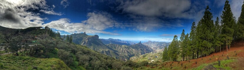 Panoramic view of lush mountain landscape under a vibrant cloudy sky