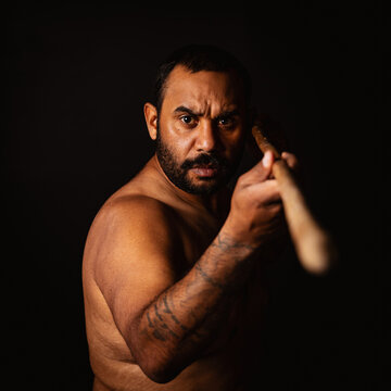 Shirtless aboriginal man holding a wooden spear