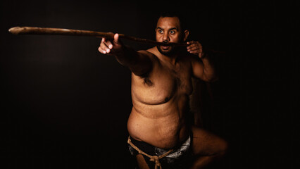 Shirtless aboriginal man holding a wooden spear