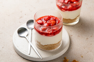 No bake individual cheesecake in glass with strawberry topping. Cheesecake cups. Summer cold parfait. Trifle with berry sauce. Home cooking. Selective focus.