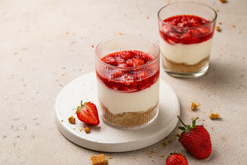 No bake individual cheesecake in glass with strawberry topping. Cheesecake cups. Summer cold parfait. Trifle with berry sauce. Home cooking. Selective focus, copy space.