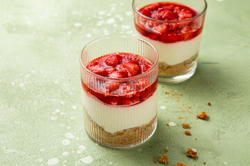 No bake individual cheesecake in glass with strawberry topping. Cheesecake cups. Summer cold parfait. Trifle with berry sauce. Home cooking. Selective focus, copy space.