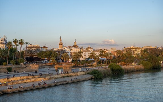 Waterfront Muelle de la sal at the river Rio Guadalquivir with Monumento a la Tolerancia, in the back bell tower La Giralda, sunset, Sevilla, Andalusia, Spain