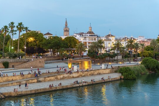 Waterfront M&uuml;lle de la sal at the river Rio Guadalquivir with Monumento a la Tolerancia, in the back La Giralda, blue hour, Sevilla, Andalusia, Spain