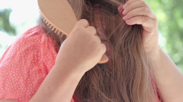 woman combing long brown hair, tangles fallen hair wound on brush pins, hair loss, health, treatment alopecia, hormonal imbalance