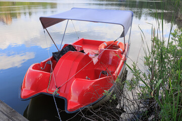 Red catamaran on the pier near the river bank